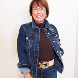 Woman wearing a denim jacket with gold buttons against a white background
