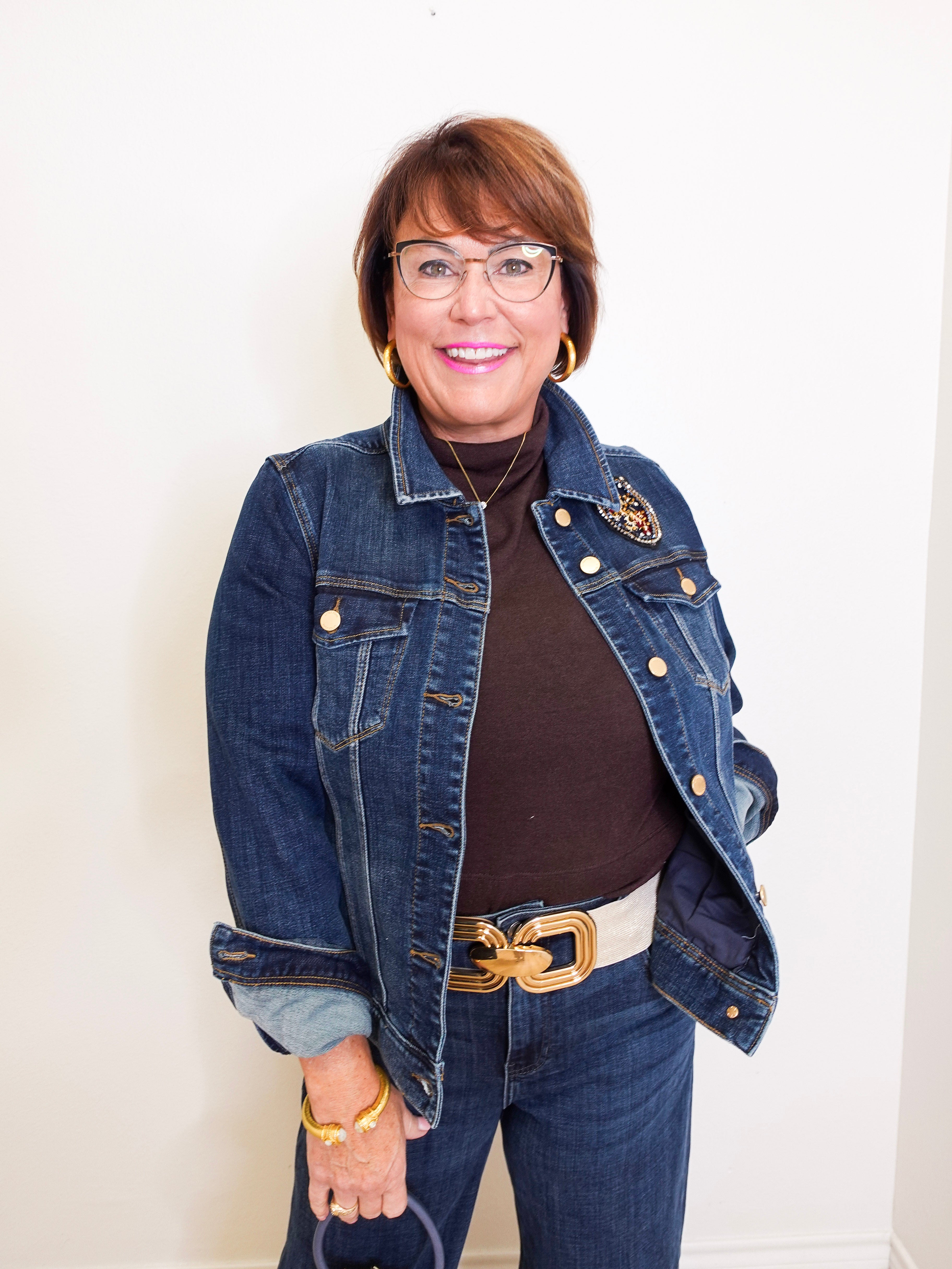 Woman wearing a denim jacket with gold buttons against a white background