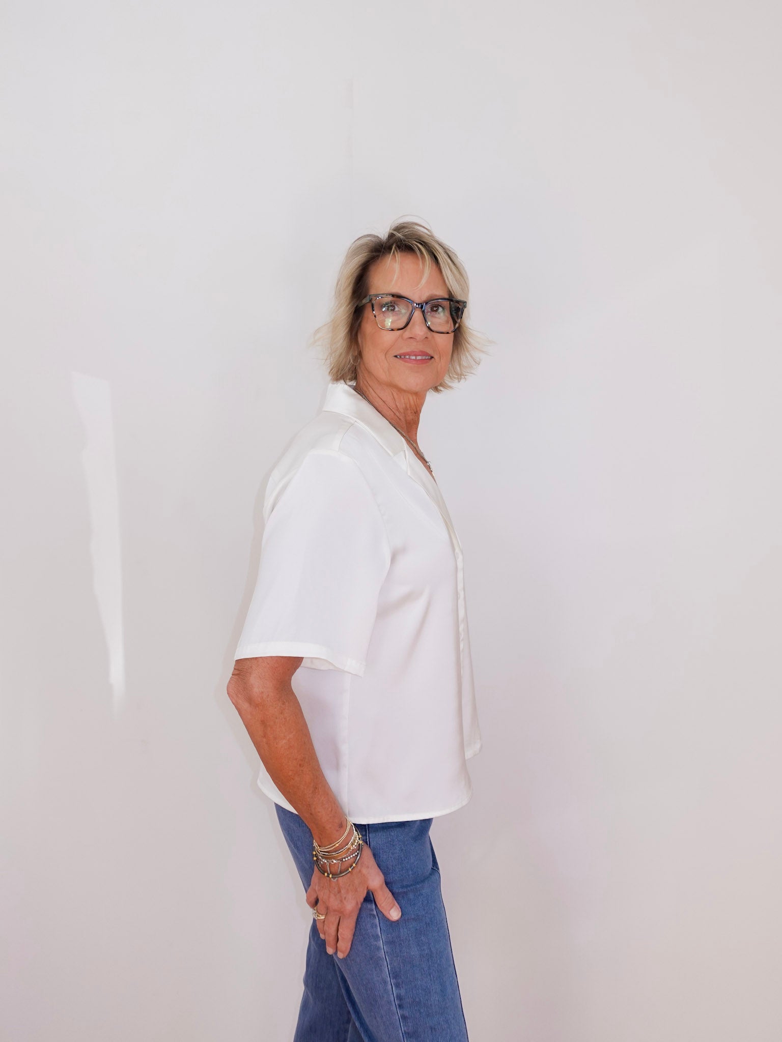 Person wearing a white shirt and blue jeans against a plain background
