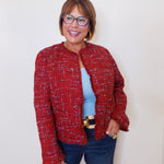 Woman wearing a red tweed jacket and blue jeans against a white background