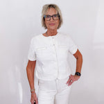 Woman wearing a white outfit with glasses against a plain background