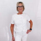 Woman wearing a white outfit with glasses against a plain background