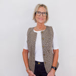Woman wearing a patterned vest over a white shirt on a plain background