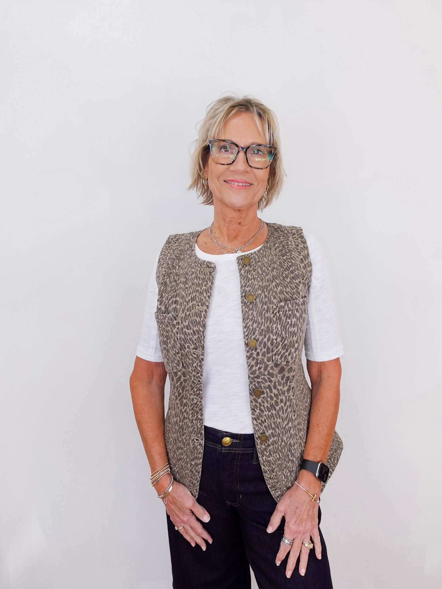 Woman wearing a patterned vest over a white shirt on a plain background