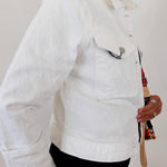 Person wearing a white jacket holding a colorful bag against a plain background
