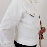 Person wearing a white jacket holding a colorful bag against a plain background