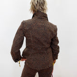 A person shown from behind wearing a brown leopard-print jacket and matching pants against a plain white wall.