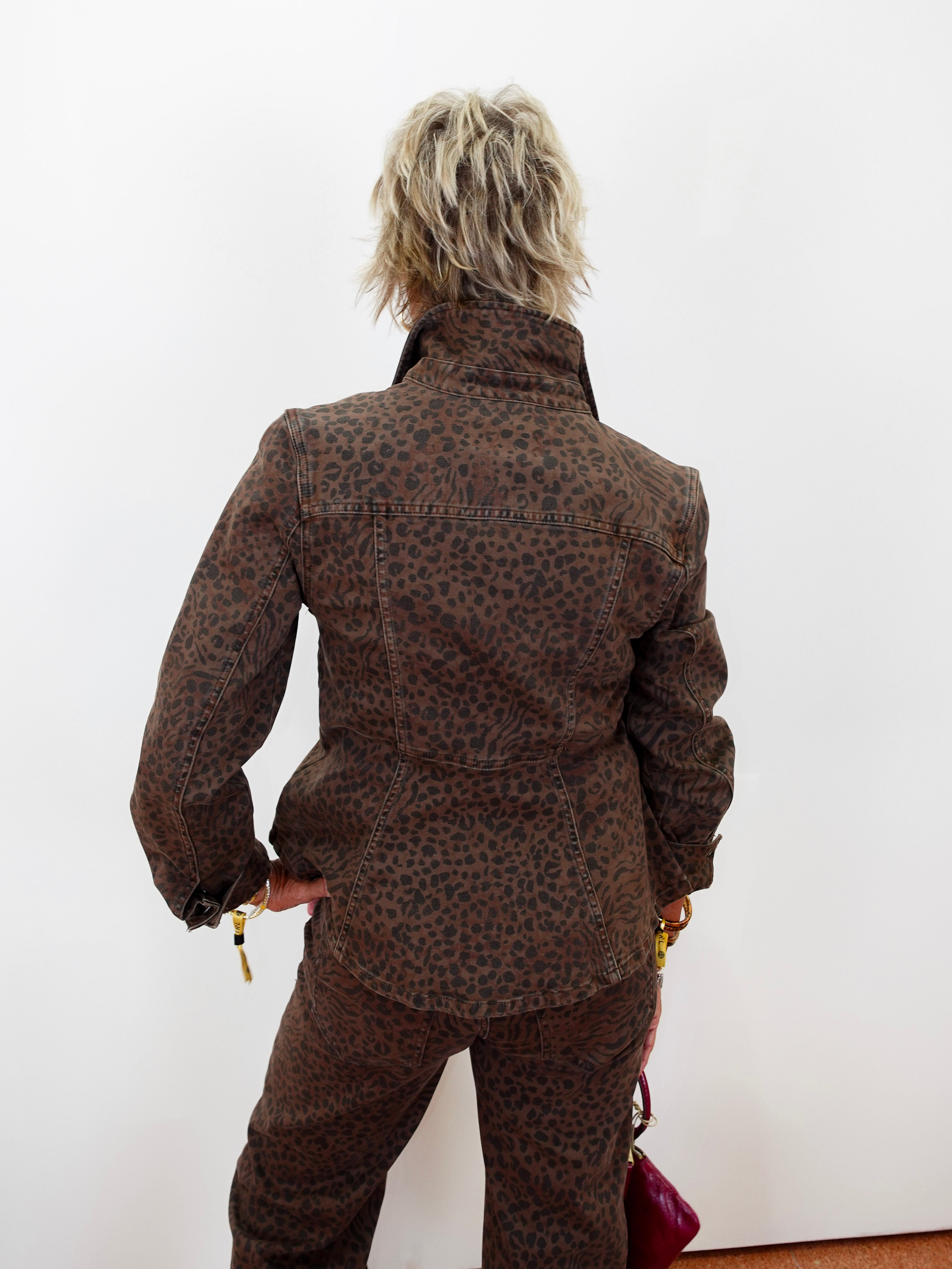 A person shown from behind wearing a brown leopard-print jacket and matching pants against a plain white wall.