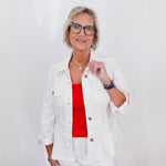 Woman wearing a white jacket over a red top with a plain background