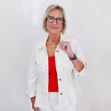 Woman wearing a white jacket over a red top with a plain background