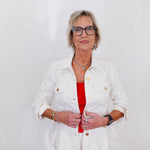 Woman wearing a white jacket over a red top on a plain background