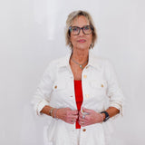 Woman wearing a white jacket over a red top on a plain background
