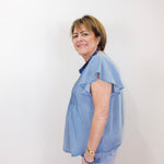 Woman wearing a light blue blouse with ruffled sleeves against a white background