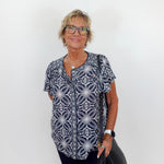 Woman wearing a patterned shirt and glasses against a white background