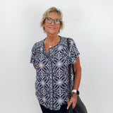 Woman wearing a patterned shirt and glasses against a white background