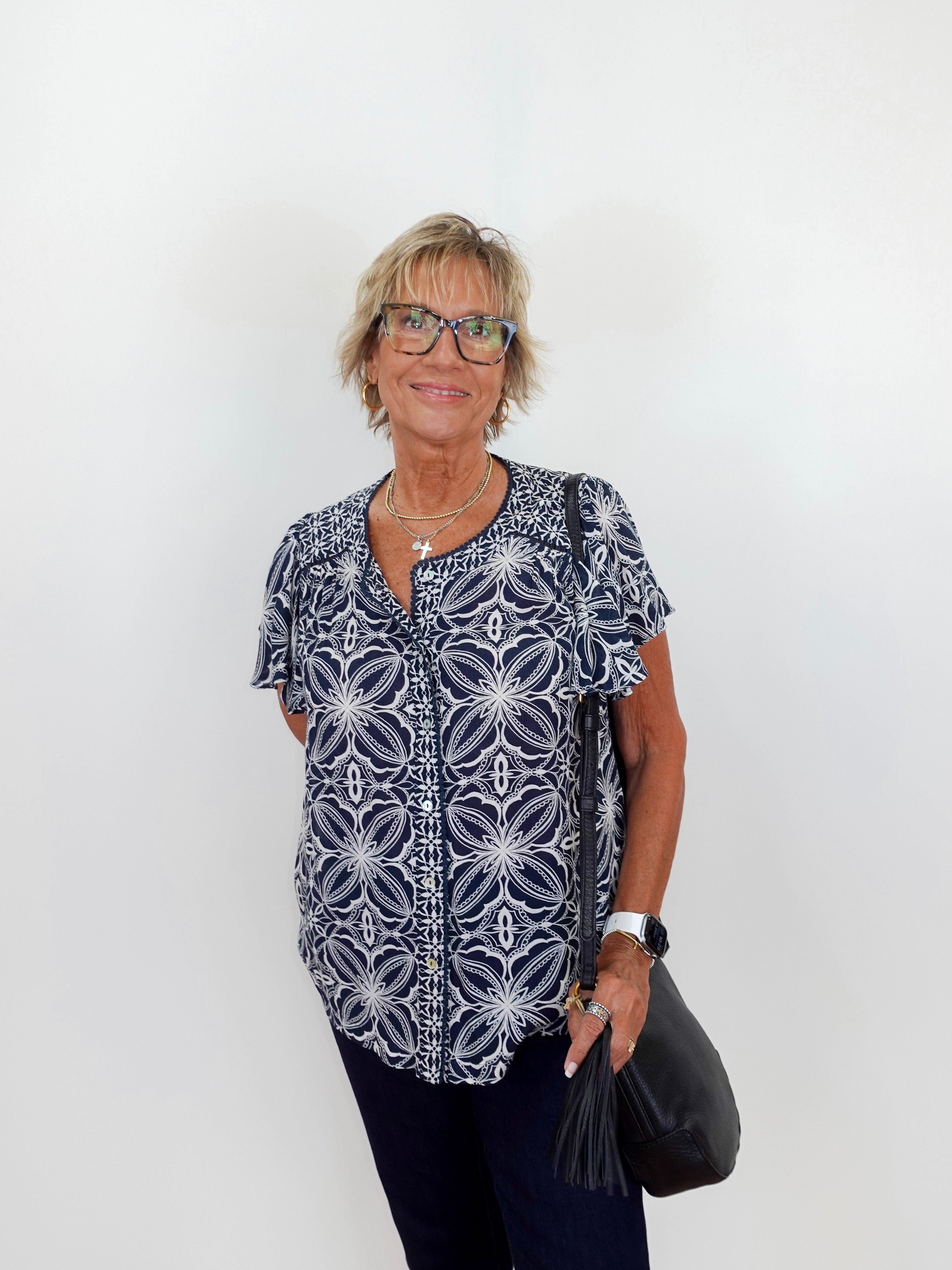 Woman wearing a patterned shirt and glasses against a white background