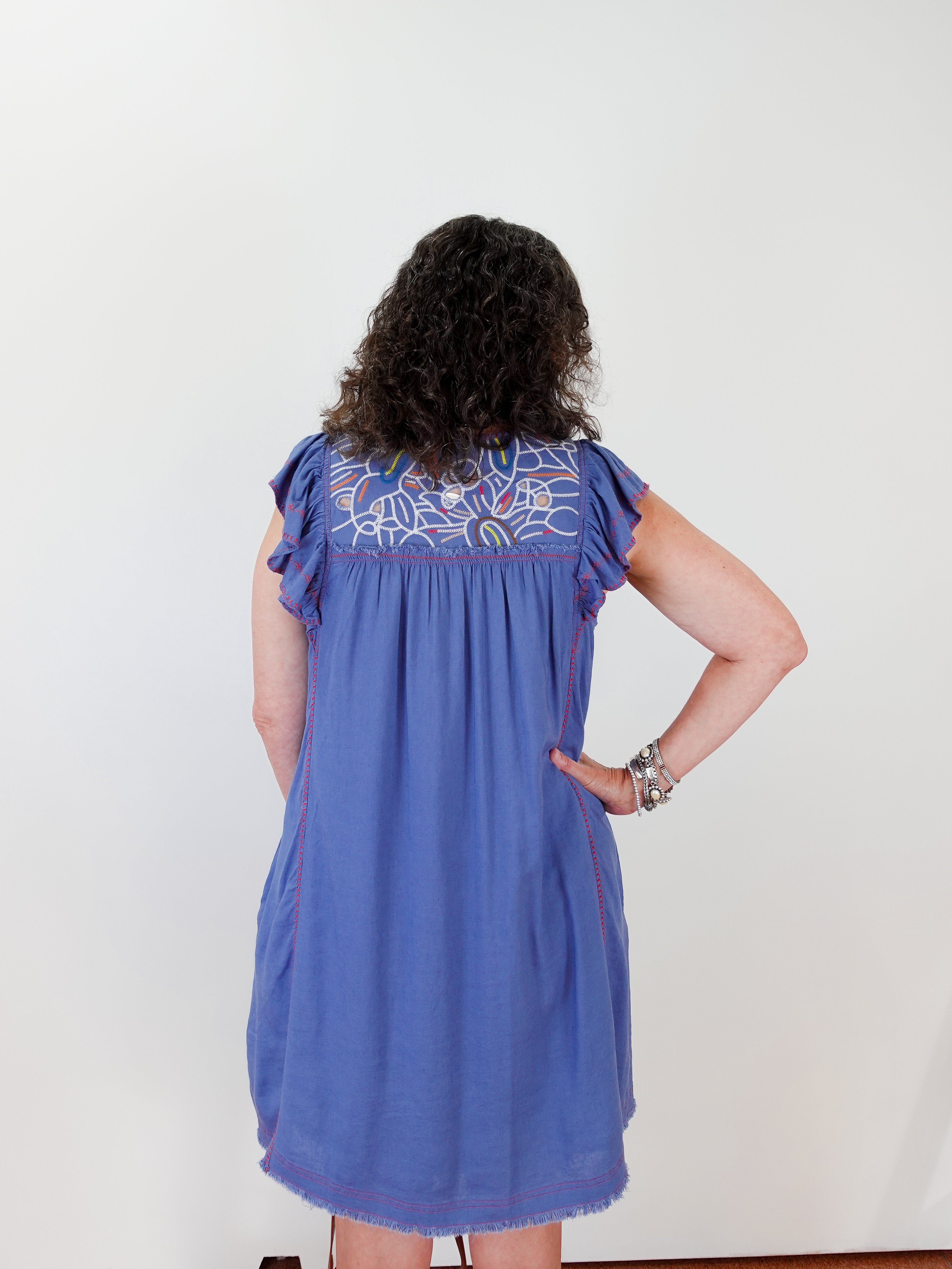 Woman wearing a blue dress with floral embroidery on a white background