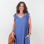 Woman wearing a blue dress with floral embellishments on a white background