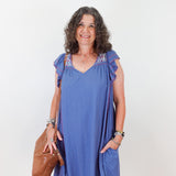 Woman wearing a blue dress with floral embellishments on a white background