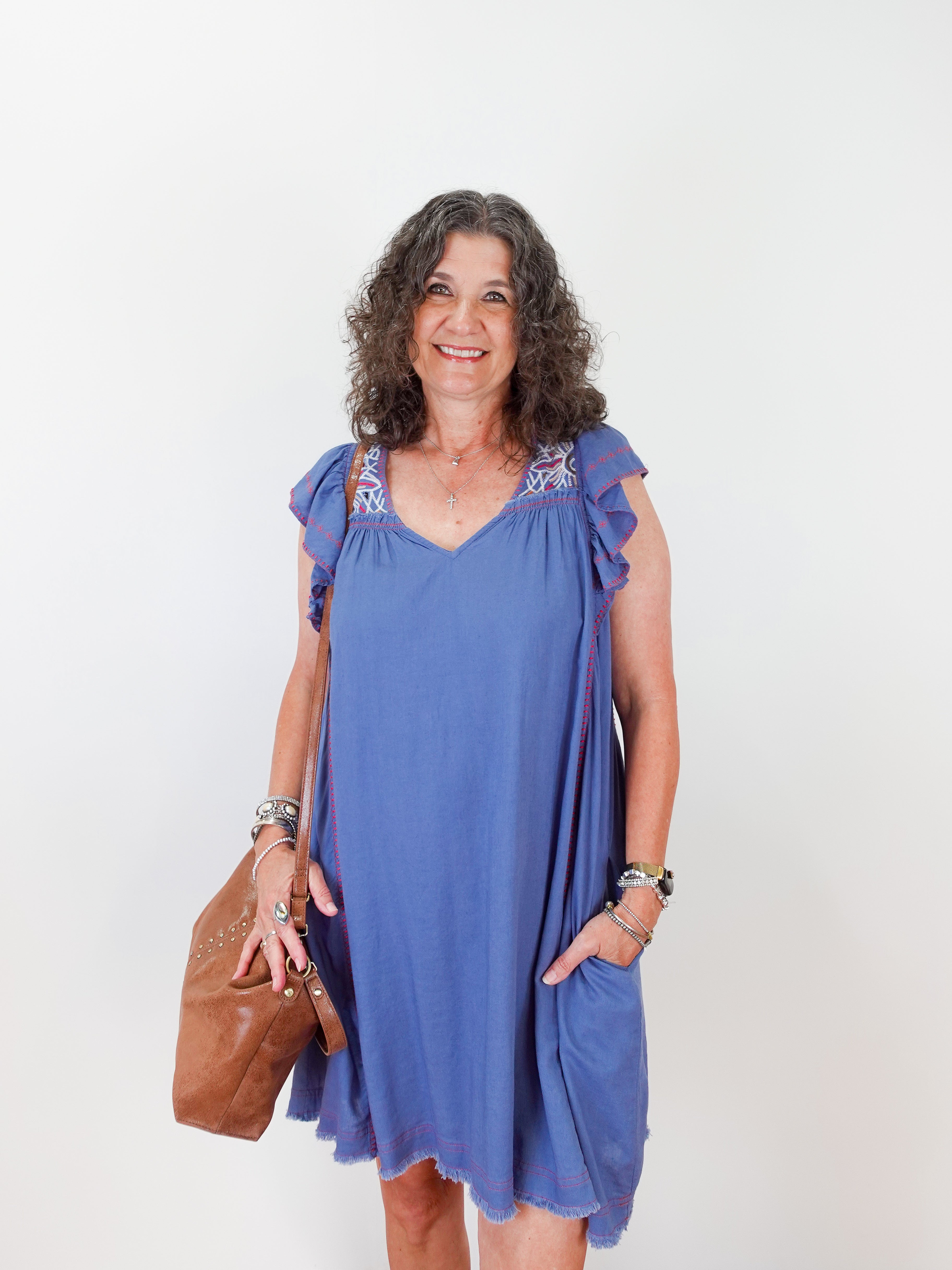 Woman wearing a blue dress with floral embellishments on a white background