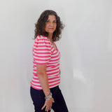 Woman wearing a pink and white striped shirt and black pants against a white background