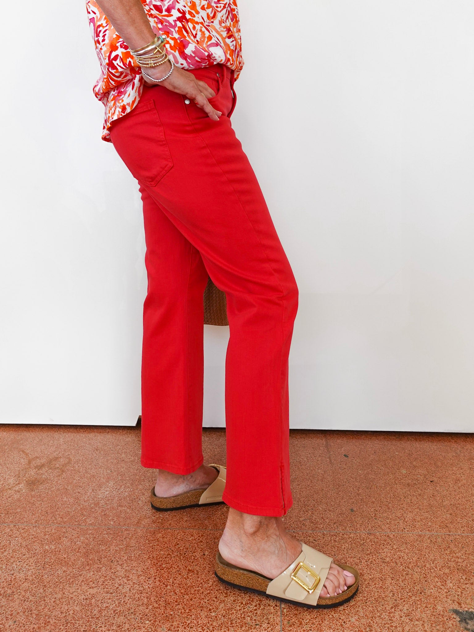 Person wearing red pants and a colorful top on a plain background