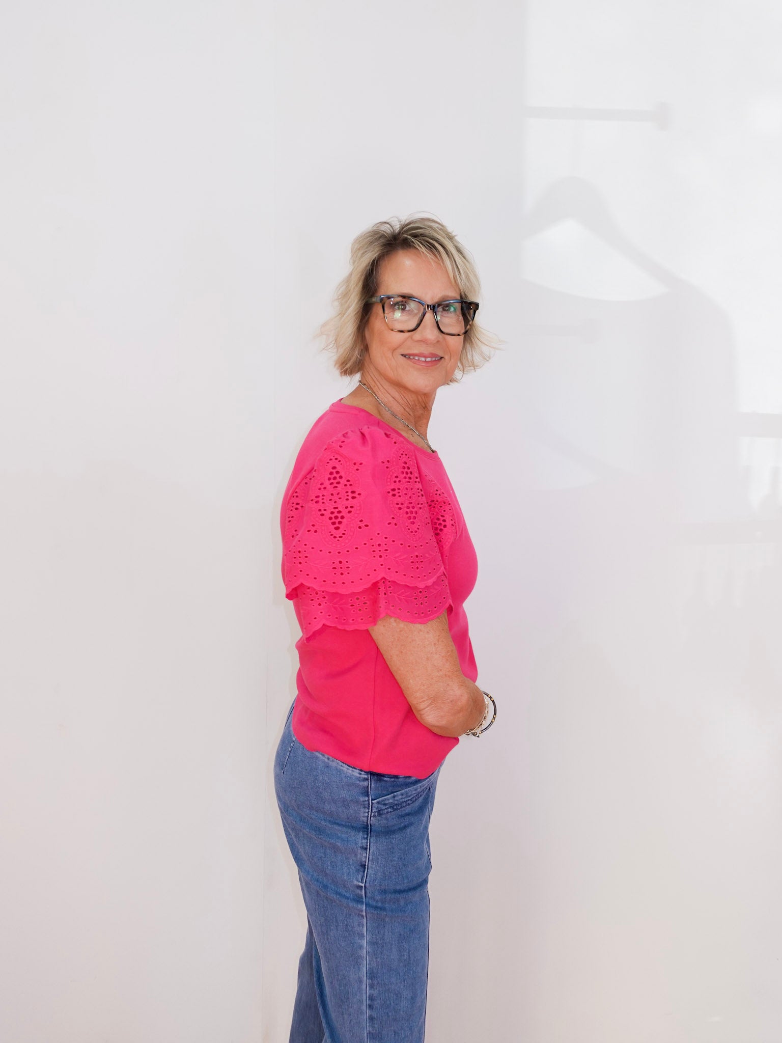 Person wearing a pink top and blue jeans against a white background