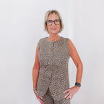 Woman wearing a leopard print sleeveless top and pants against a white background