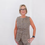 Woman wearing a leopard print sleeveless top and pants against a white background