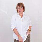 Person wearing a white shirt and patterned pants against a plain background