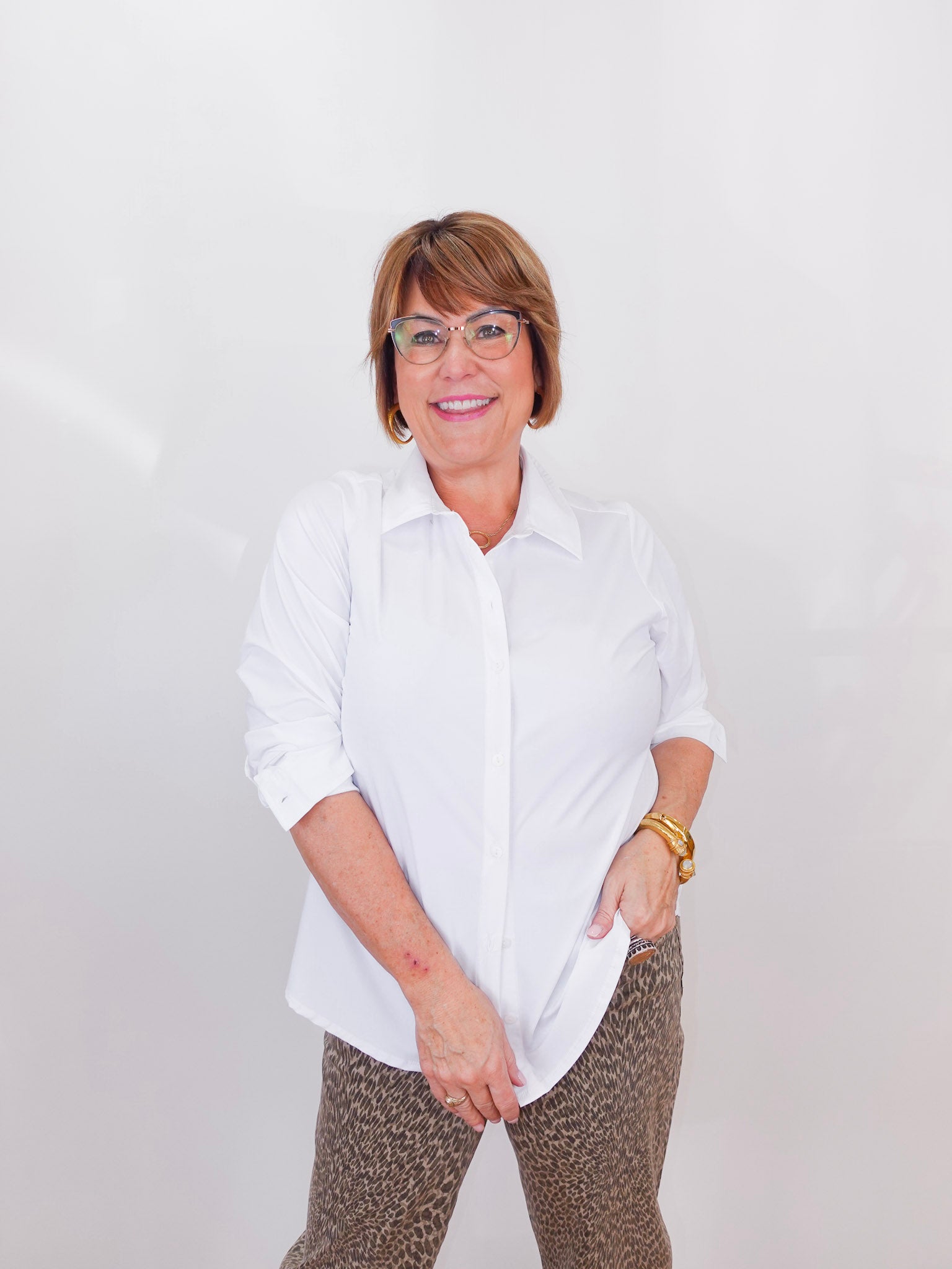 Person wearing a white shirt and patterned pants against a plain background