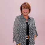 Woman wearing a patterned jacket and glasses against a pink background