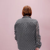 Person wearing a patterned shirt against a pink background