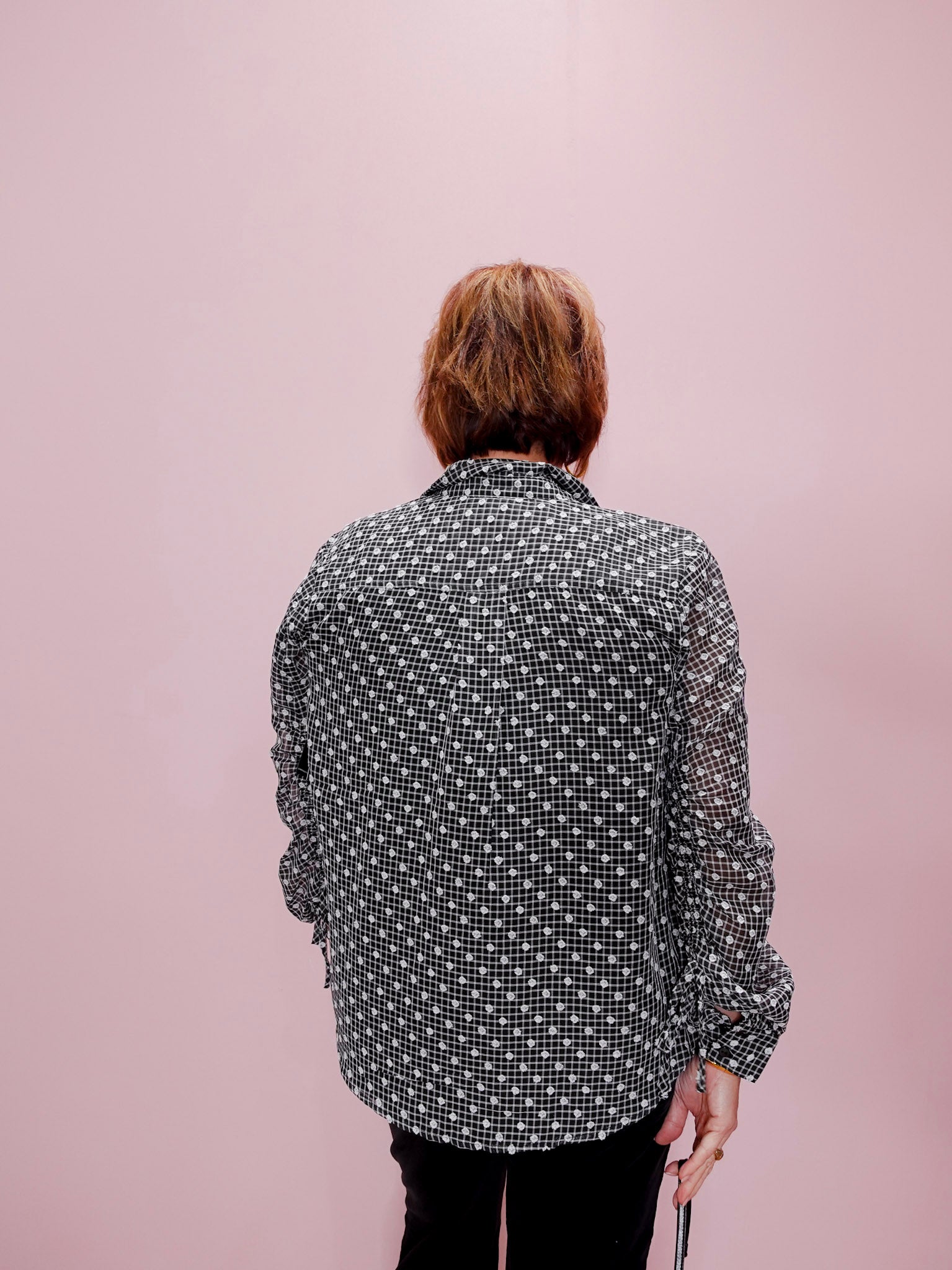 Person wearing a patterned shirt against a pink background