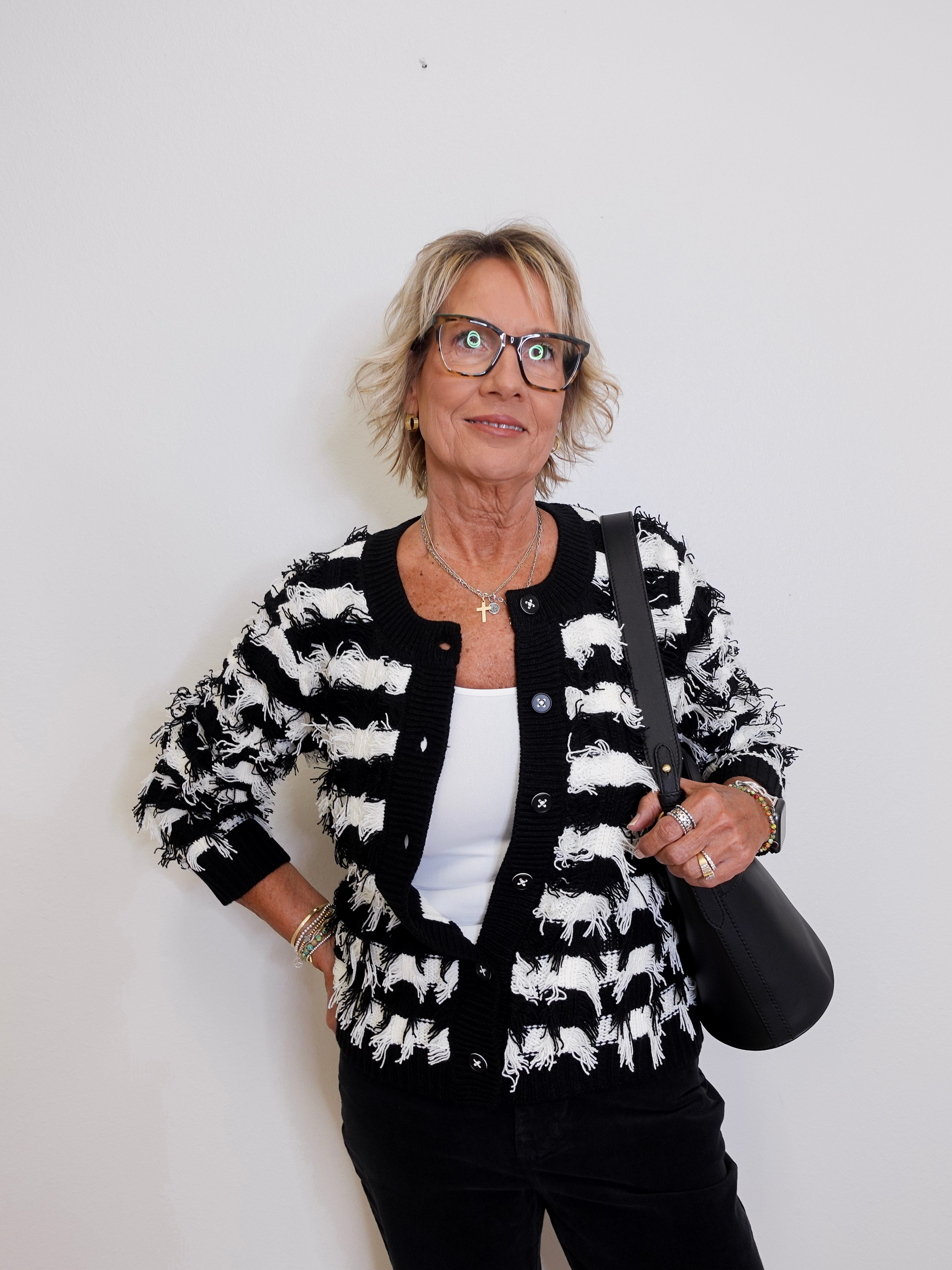 Woman wearing a black and white patterned jacket against a plain background