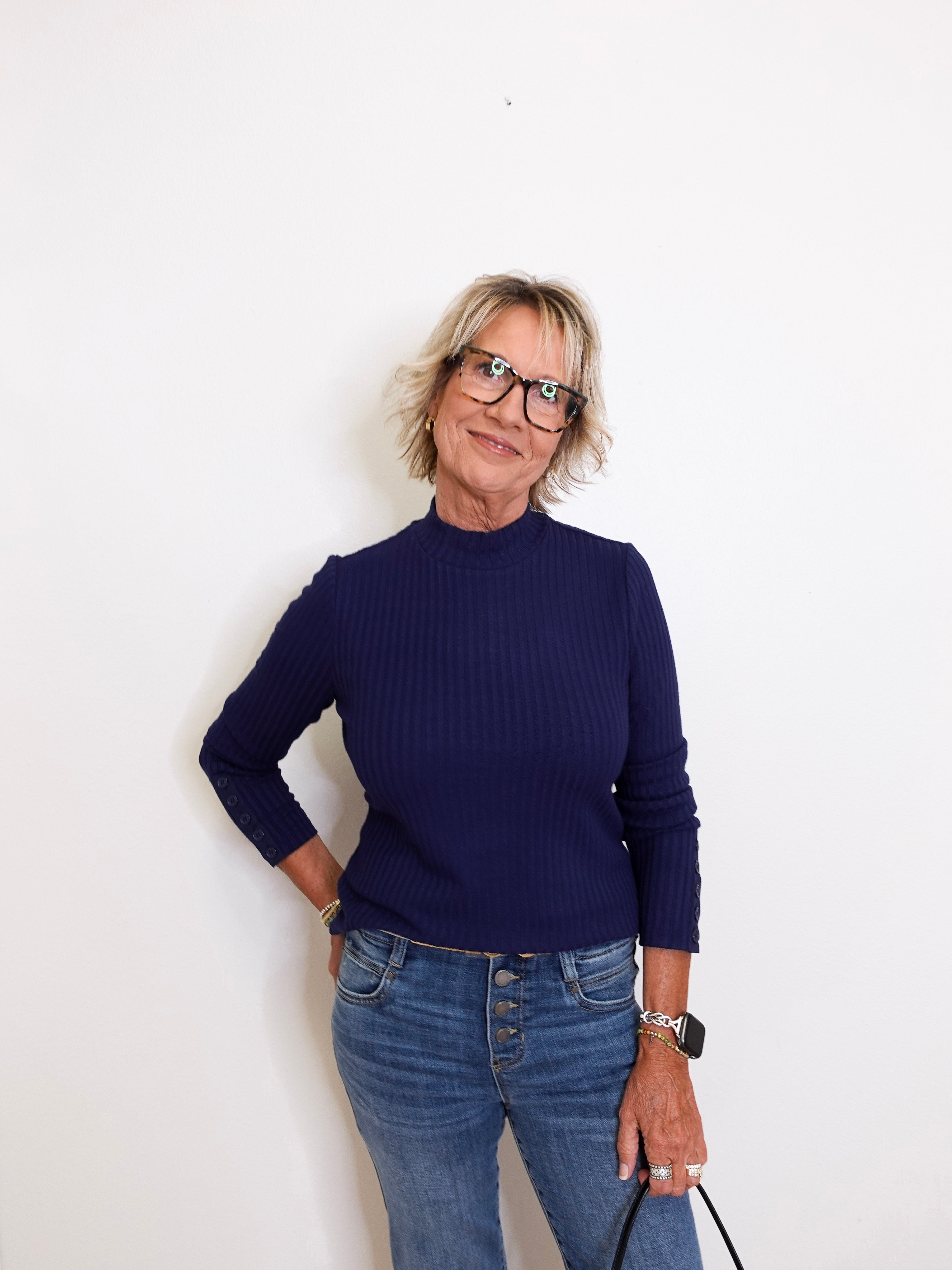 Person wearing a navy sweater and blue jeans against a white background