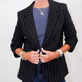 Person wearing a black pinstripe blazer over a blue shirt with a plain background