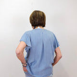 Person wearing a light blue t-shirt and jeans against a plain background