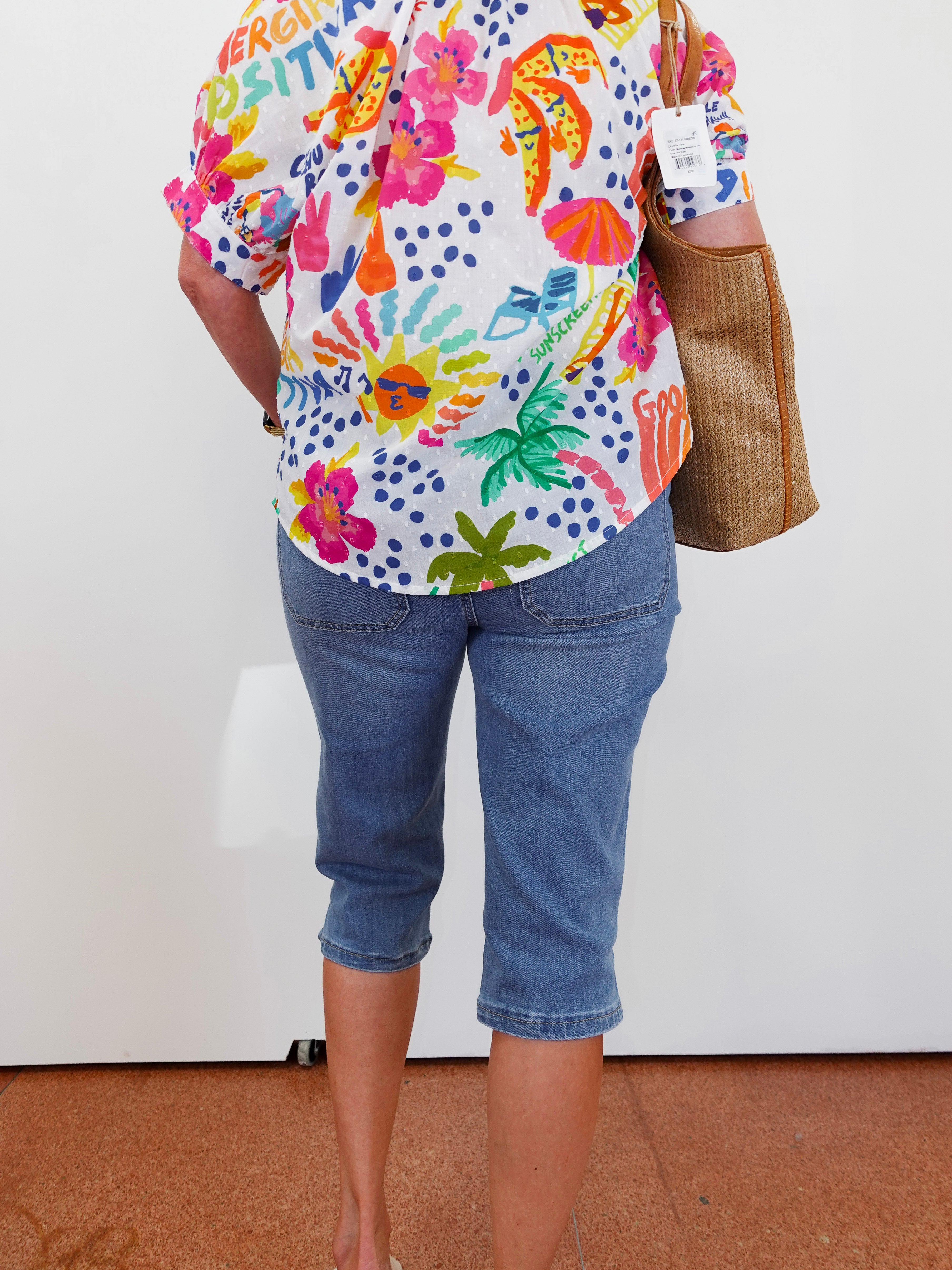 Person wearing a colorful floral shirt and blue jeans with a white background