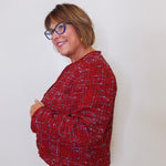 Person wearing a red patterned sweater against a white background