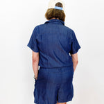 Person wearing a blue outfit with a white cap on a plain background