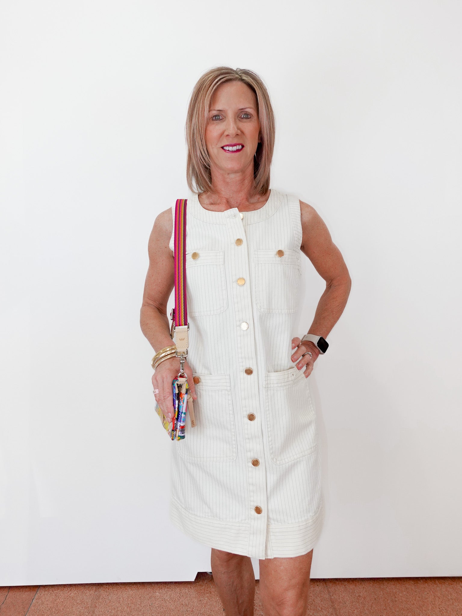 Woman in a white dress holding colorful items against a white background