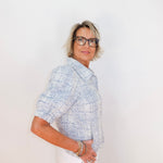 Woman wearing a patterned blouse and glasses against a white background