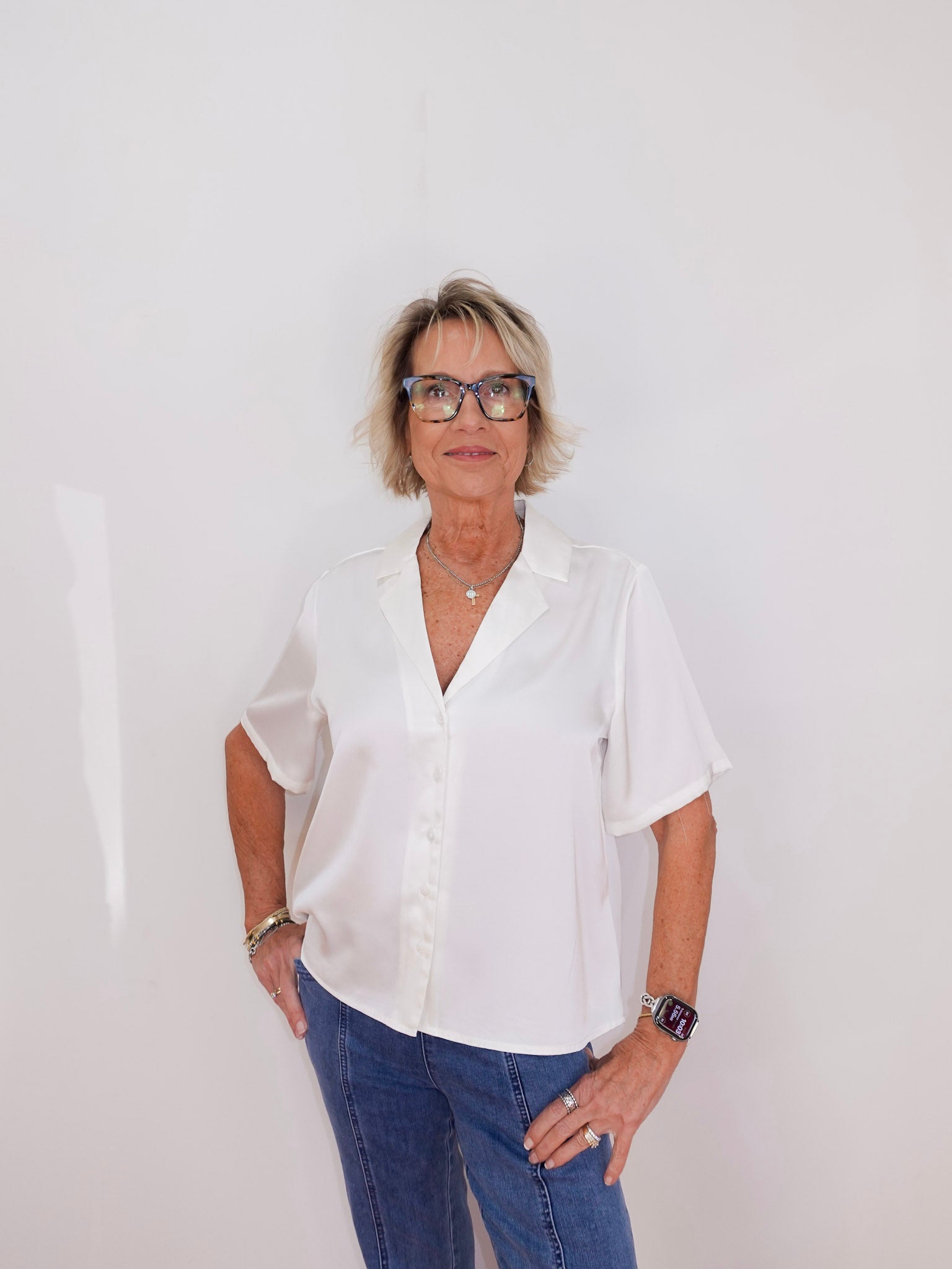 Person wearing a white shirt and blue jeans against a plain background