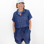 Woman wearing a blue romper and white cap with text on a white background