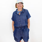Woman wearing a blue romper and white cap with text on a white background