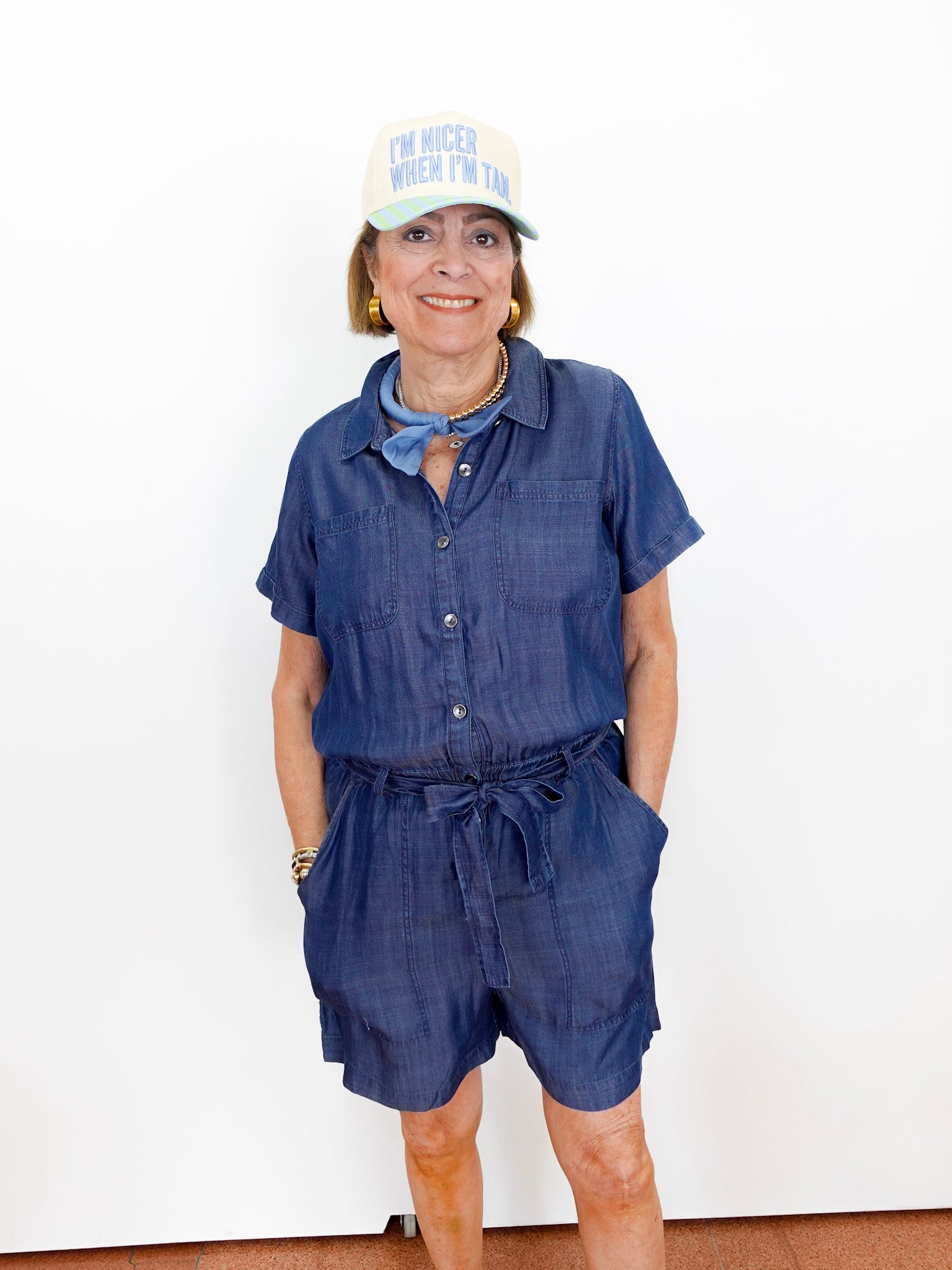 Woman wearing a blue romper and white cap with text on a white background