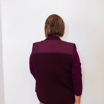 Person wearing a purple vest against a white wall