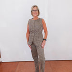 Woman wearing a patterned outfit standing against a white wall.