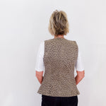 Person wearing a patterned vest over a white shirt on a plain background